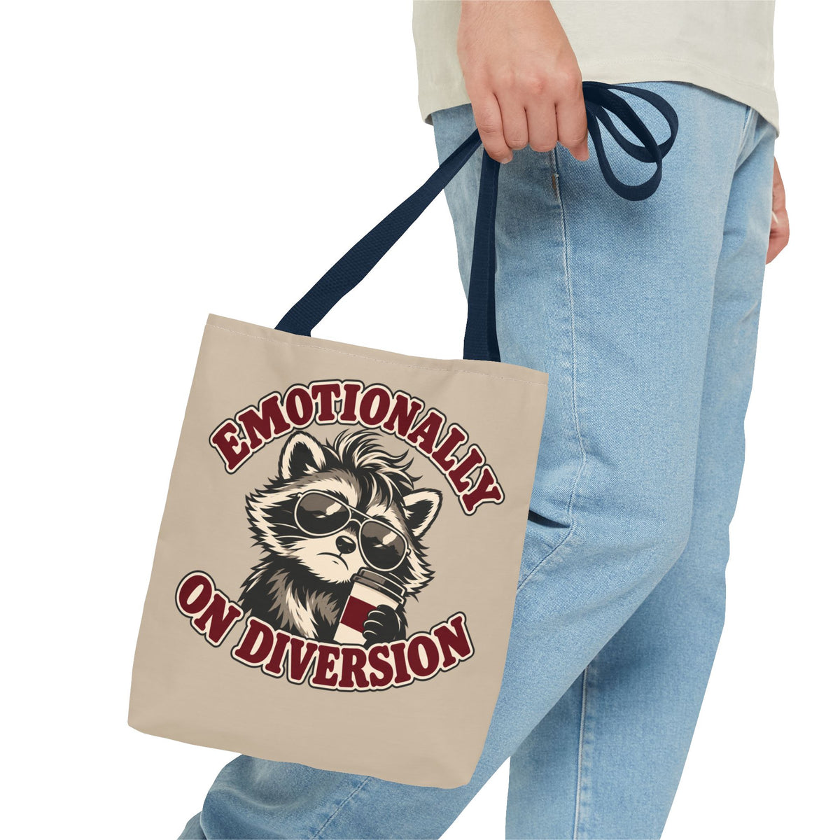 Emotionally on Diversion raccoon tote with Navy handles, carried by hand