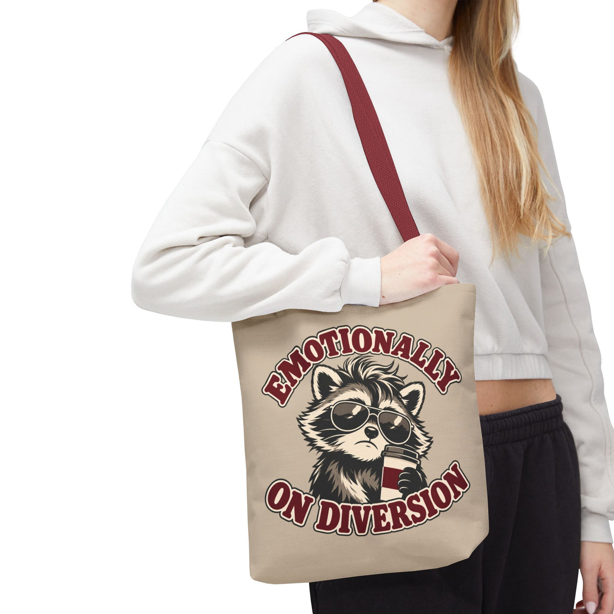 Emotionally on Diversion raccoon tote with Red handles, worn over a woman's shoulder